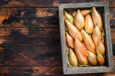 Tahta bir pazar kutusunda çiğ Shallot soğanı soğanı. Karanlık ahşap arka plan. Üst Manzara. Boşluğu kopyala