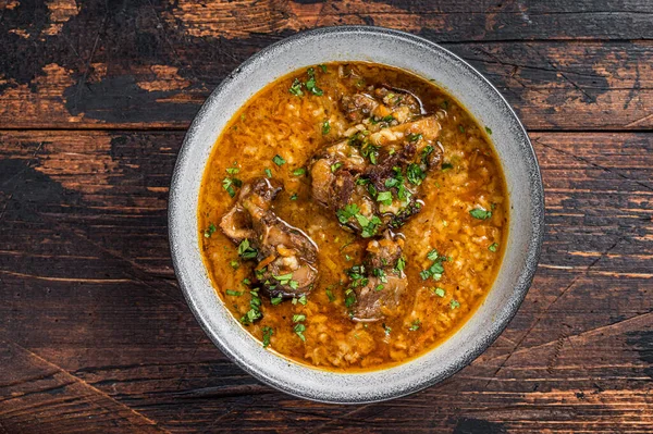 Zuppa di carne di manzo Kharcho con riso, pomodori e spezie in una ciotola. Fondo in legno scuro. Vista dall'alto — Foto Stock