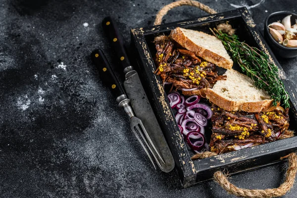 Pulled pork Sandwich with smoked pork meat in a wooden tray. Black background. Top view. Copy space