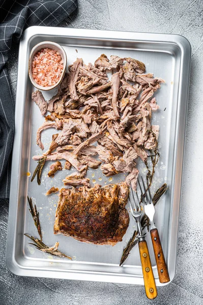 Bbq grilled puilled pork meat in a steel baking tray. White background. Top view