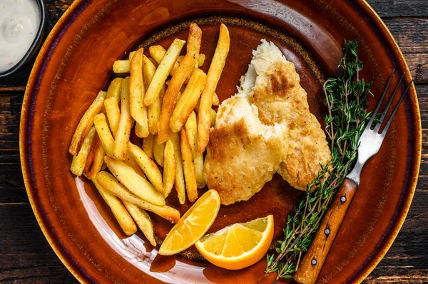 Fisk och Chips brittisk snabbmat med pommes frites och tartarsås på en rustik tallrik. Mörk trä bakgrund. Ovanifrån — Stockfoto