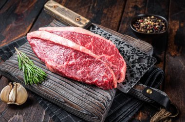 Kasap panosunda et satırlı çiğ sığır eti bifteği. Karanlık woden arka plan. Üst görünüm