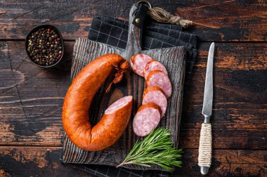 Alman füme sosisi ahşap bir köy tahtasında kekik ile. Koyu ahşap arka plan. Üst görünüm