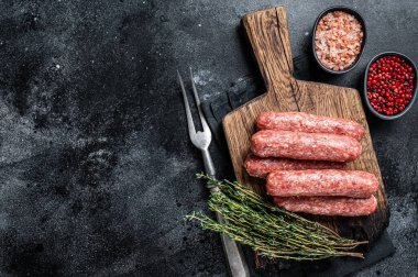 Ahşap bir tahtanın üzerinde pişmemiş çiğ et ve kuzu eti kebabı sosisi. Siyah arka plan. Üst Manzara. Boşluğu kopyala