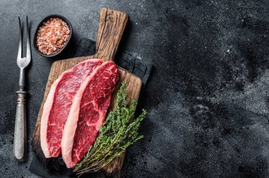 Pişmemiş çiğ biftek ya da ahşap tahtada sığır eti bifteği. Siyah arka plan. Üst Manzara. Boşluğu kopyala