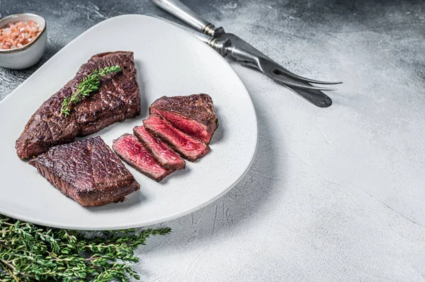 Filete de carne de res rump asado en rodajas en un plato con tomillo. Fondo blanco. Vista superior. Copiar espacio —  Fotos de Stock