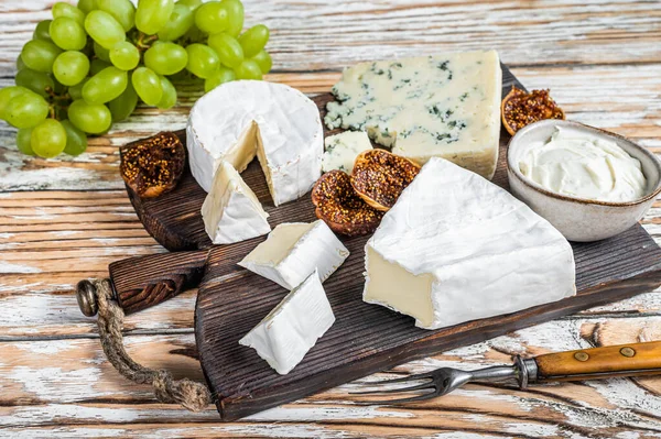 Tábua de queijo com brie, Camembert, Gorgonzola e queijo cremoso azul. Fundo de madeira branco. Vista superior — Fotografia de Stock
