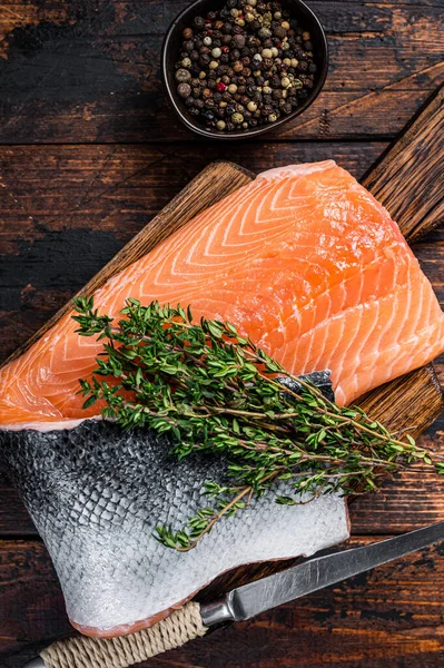 Filetto di salmone pesce su una tavola di legno con erbe e sale. Fondo in legno scuro. Vista dall'alto — Foto Stock