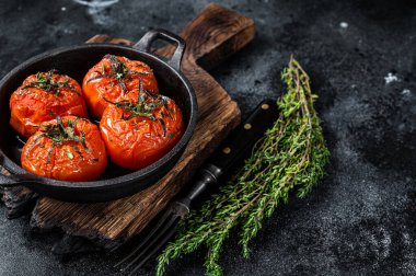 Tavada kekik olan kızarmış kiraz domatesleri. Siyah arka plan. Üst Manzara. Boşluğu kopyala