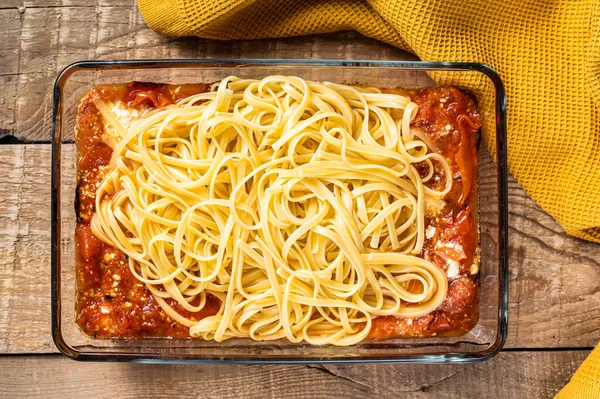 Oven baked feta Spaghetti pasta in baking dish. Wooden background. Top view — Stock Photo, Image