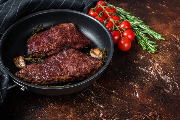Gegrilde denver beef steak in een pan met rozemarijn. Donkere achtergrond. Bovenaanzicht. Kopieerruimte — Stockfoto