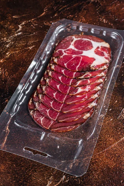 Italienskt skivat charkuterikött i vakuumförpackningar. Mörk bakgrund. Ovanifrån — Stockfoto