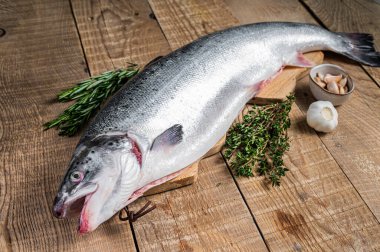 Tahta bir kichen masasında otlarla birlikte çiğ somon balığı. Ahşap arka plan. Üst görünüm