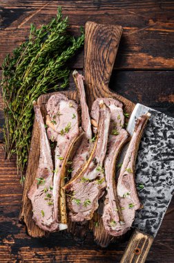 Kasap panosunda et satırıyla ızgara koyun pirzolası. Koyu ahşap arka plan. Üst görünüm