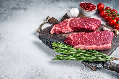 Çiğ Denver siyah angus organik bifteğini bir kasap kesme tahtasına otlarla kesti. Beyaz arka plan. Üst Manzara. Boşluğu kopyala