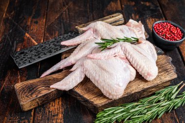 Et satırıyla kasap tahtasında pişmemiş çiğ tavuk kanadı. Karanlık ahşap arka plan. Üst görünüm