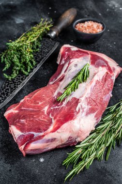 Taze çiğ koyun eti, kasap bıçağıyla omuz eti. Siyah arka plan. Üst görünüm