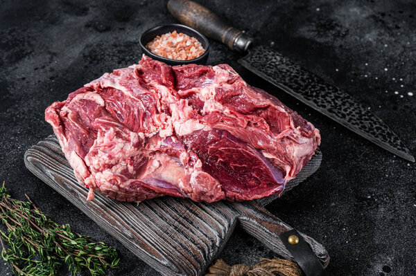 Raw Boneless Leg of Lamb meat on wooden cutting board. Black background. Top view