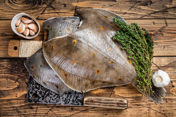 Raw flounder flatfish on butcher board with cleaver. wooden background. Top view