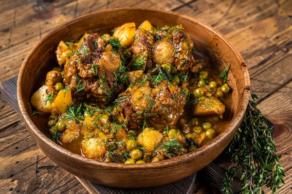 Codini di agnello stufato con verdure in un piatto di legno. sfondo in legno. Vista dall'alto — Foto Stock