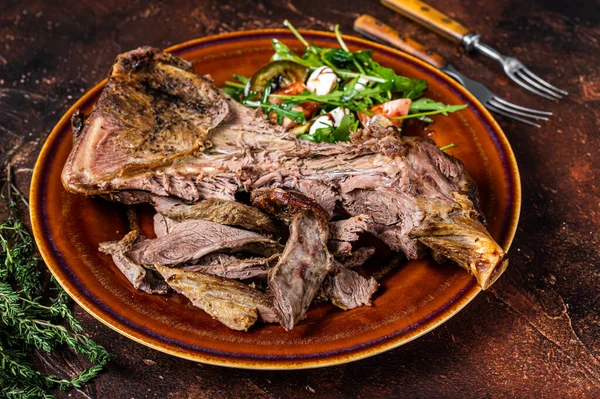 Grilled goat or lamb mutton shoulder meat in a rustic plate with salad. Dark background. Top view — Stock Photo, Image