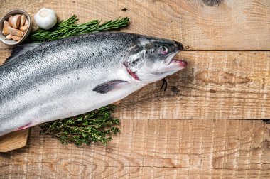 Tahta bir kichen masasında otlarla birlikte çiğ somon balığı. Ahşap arka plan. Üst Manzara. Boşluğu kopyala