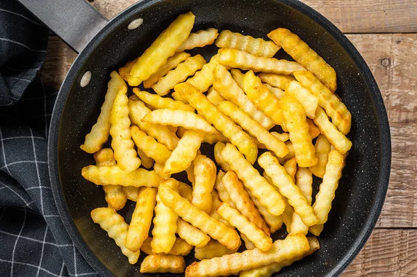 Fried Crinkle oven Papas fritas palitos en una sartén. Fondo de madera. Vista superior —  Fotos de Stock