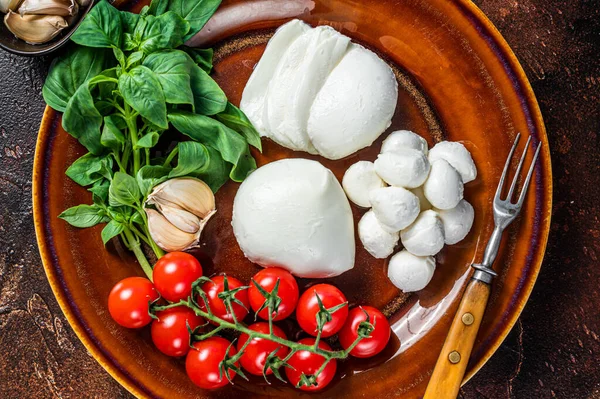 Mozzarella cheese, basil and tomato cherry ready for cooking Caprese salad. Dark background. Top view — Stock Photo, Image