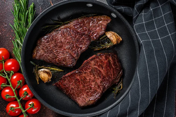 Grilovaný hovězí steak z denveru v pánvi s rozmarýnem. Tmavé pozadí. Horní pohled — Stock fotografie
