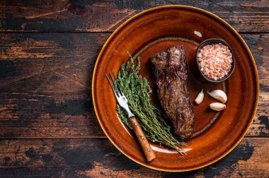 Kırsal tabakta ızgara pala bifteği, otlar ve pembe tuz. Koyu ahşap arka plan. Üst Manzara. Boşluğu kopyala