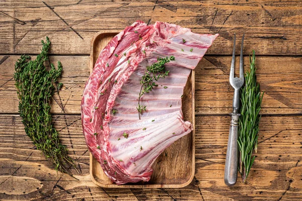 Ahşap tepside otlu kuzu pirzola rafı. Ahşap arka plan. Üst görünüm