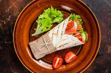 Balık somon ve sebzeli rulo sandviç. Karanlık arka plan. Üst görünüm