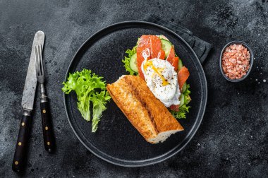 Benedict yumurtalı sandviç tostu, füme somon ve ekmekle avokado. Siyah arka plan. Üst görünüm