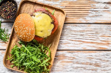 Biftek, domates, peynir ve roka ile büyük bir çizburger. Ahşap arka plan. Üst Manzara. Boşluğu kopyala