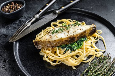 Fırınlanmış Halibut balığı bifteği ve ıspanaklı makarna. Siyah arka plan. Üst görünüm