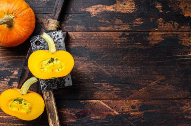 Çiğ portakal kabağı dilimliyorum. Koyu ahşap arka plan. Üst Manzara. Boşluğu kopyala