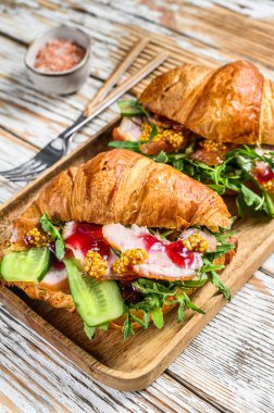 Tahtada jambon ve peynirli sandviç kruvasanı. Beyaz ahşap arka plan. Üst görünüm