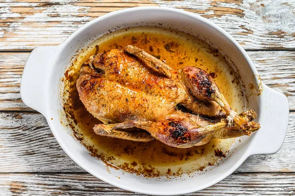 Baked whole farm duck in a baking dish. White wooden background. Top view — Stock Photo, Image