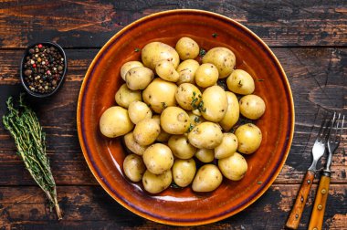 Yeni haşlanmış patates, tereyağı ve doğranmış dereotlu. Karanlık ahşap arka plan. Üst görünüm