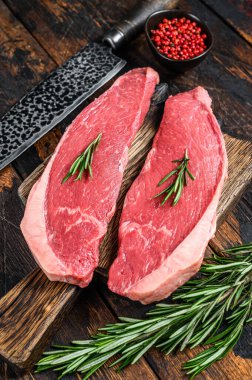 Kesme tahtasında çiğ sığır eti sığır filetosu bifteği. Koyu ahşap arka plan. Üst görünüm