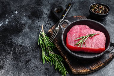 Tavada biberiyeli taze çiğ ton balığı bifteği. Siyah arka plan. Üst Manzara. Boşluğu kopyala