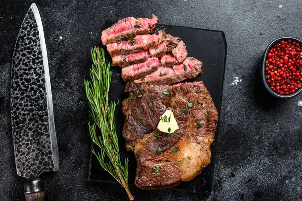 Misket tahtasında ızgara Chuck 'ın gözleme bifteği. Siyah arka plan. Üst görünüm