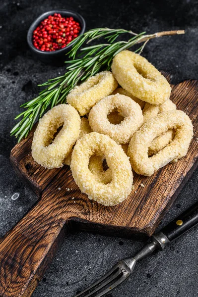 Lulas crocantes cruas anéis em migalhas de pão em uma placa de corte. Fundo preto. Vista superior — Fotografia de Stock