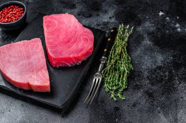 Mermer kesim tahtasında çiğ ton balığı bifteği. Siyah arka plan. Üst Manzara. Boşluğu kopyala