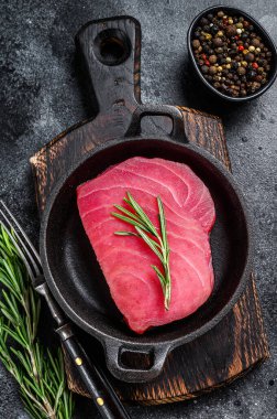 Tavada biberiyeli çiğ ton balığı filetosu. Siyah arka plan. Üst görünüm