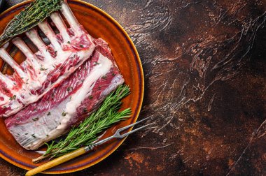 Çiğ taze kuzu pirzolası ve yeşil otlar. Karanlık arka plan. Üst Manzara. Boşluğu kopyala