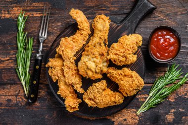 Tavuk budu, bacak, kanat ve göğüs kanadı şeritleri. Karanlık ahşap arka plan. Üst görünüm