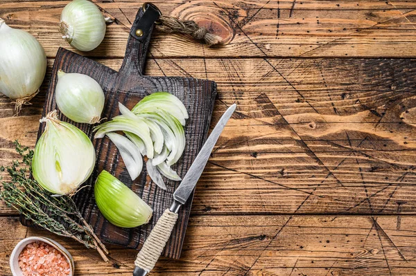 Tahta kesme tahtasında dilimlenmiş çiğ beyaz soğan. Ahşap arka plan. Üst Manzara. Boşluğu kopyala