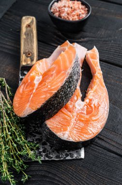 Kasap satırında taze çiğ somon bifteği. Siyah ahşap arka plan. Üst görünüm