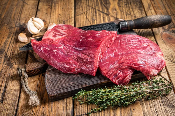 Flanc steaks de bœuf cru sur une planche à découper boucher avec couteau. fond en bois. Vue du dessus — Photo